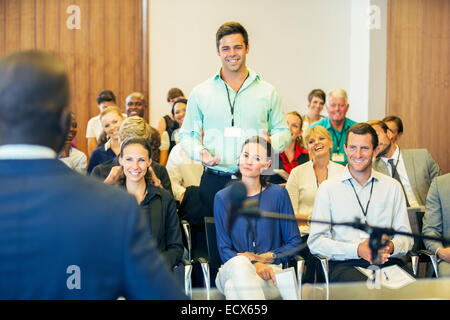 Business people attending presentation in conference room, smiling and discussing Stock Photo
