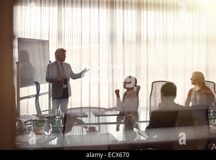 Business people attending presentation in conference room, gesturing and discussing Stock Photo