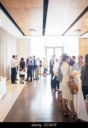 Large group of people socializing in lobby of conference center during coffee break Stock Photo