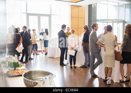 Group of conference participants standing in lobby of conference center, socializing during lunch break Stock Photo