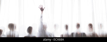 Silhouette of people behind transparent curtain, one person rising hand Stock Photo