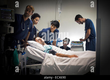 Group of doctors caring for patient in hospital ward Stock Photo