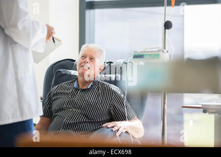 Doctor talking to patient receiving medical treatment in hospital ward Stock Photo