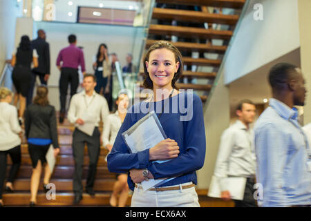 Portrait of smiling young woman standing in lobby of conference center Stock Photo