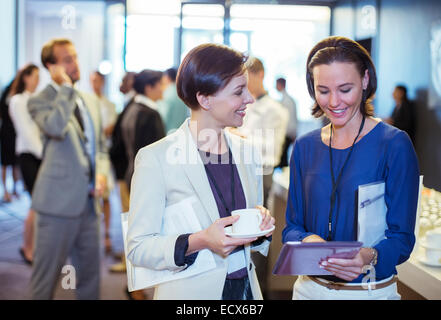 Portrait of two smiling women, talking in lobby of conference center during coffee break Stock Photo