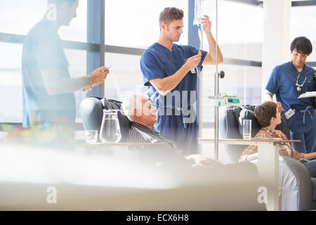 Doctors attending patients receiving intravenous infusion in hospital Stock Photo