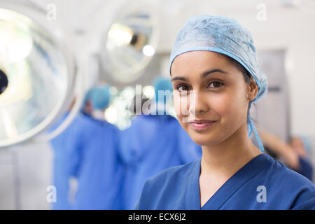 Portrait of smiling female surgical nurse wearing blue surgical cap and scrubs Stock Photo