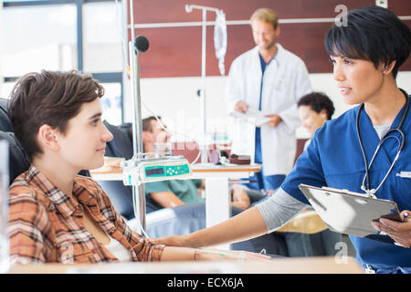 Female doctor holding clip board checking with female patient in outpatient clinic Stock Photo