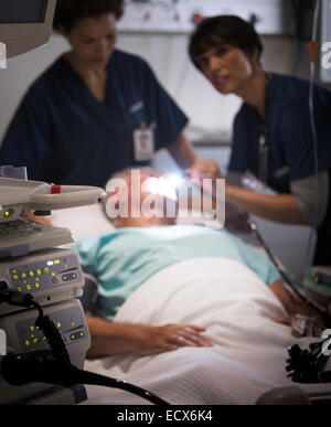 Doctor examining senior patient with flashlight in intensive care unit Stock Photo