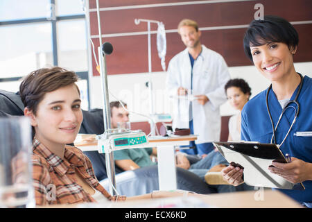 Smiling doctors checking with patients undergoing medical treatment in outpatient clinic Stock Photo