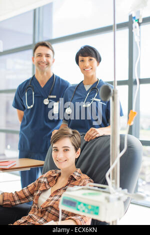 Smiling doctors standing by patient undergoing medical treatment in outpatient clinic Stock Photo