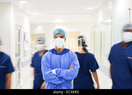 Surgeon with arms crossed, wearing scrubs standing in hospital corridor Stock Photo