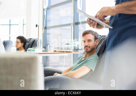 Doctor standing next to patient undergoing medical treatment in outpatient clinic Stock Photo