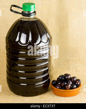 5 Litre Bottle of olive oil with olives in a small dish with copy space Stock Photo