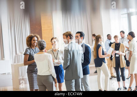 Group of business people standing in hall, smiling and talking together Stock Photo