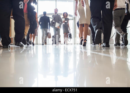 Business people rushing through office hall, reflections on tiled floor Stock Photo