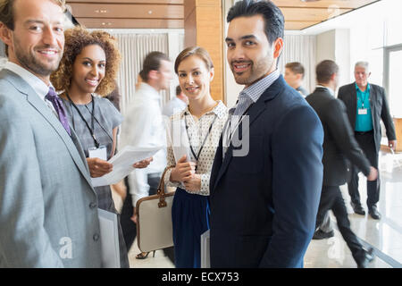 Group of business people standing in office hall, smiling and looking at camera Stock Photo