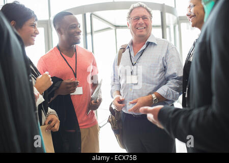 Group of business people standing in office hall, talking and smiling Stock Photo