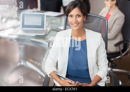 Portrait of smiling businesswoman posing with tablet pc in conference room