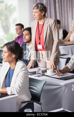 Businesswoman standing and asking question during presentation in conference room Stock Photo