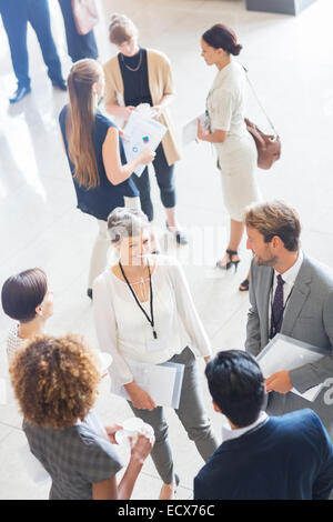 Businesswoman talking to conference participants, standing in lobby of conference center Stock Photo