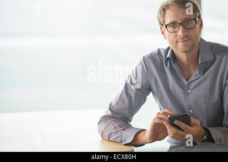 Businessman using cell phone at table Stock Photo