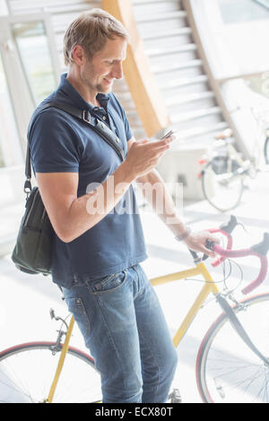 Man using cell phone and holding bicycle Stock Photo