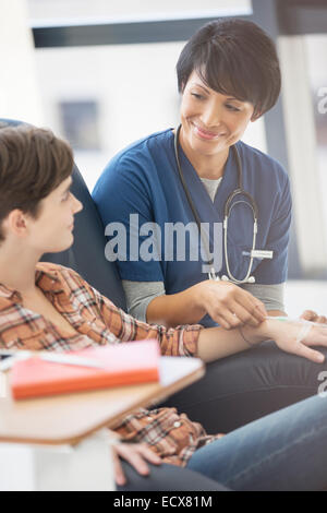Female doctor talking to young patient receiving medical treatment in hospital ward Stock Photo