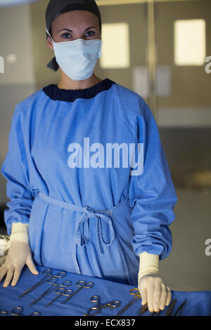 Portrait of masked surgeon with set of surgical instruments in operating theater Stock Photo