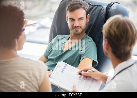 Doctor questioning patient and writing on clipboard Stock Photo