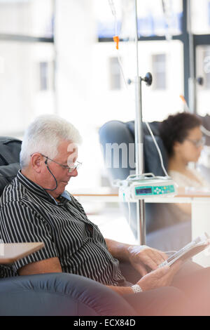 Man reading magazine, undergoing medical treatment in outpatient clinic Stock Photo