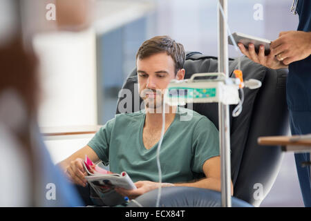Patient reading magazine, undergoing medical treatment in outpatient clinic Stock Photo