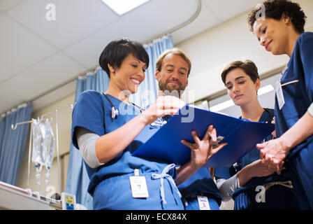 Doctors wearing scrubs, looking at documents in hospital ward Stock Photo
