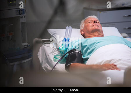 Patient lying in bed next to oxygen mask in intensive care unit Stock Photo