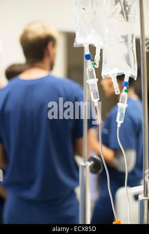 Close up of IV drip bags, doctors in background Stock Photo