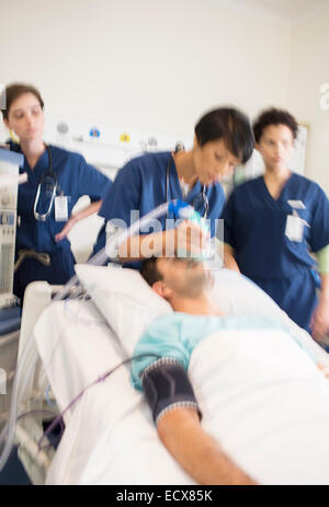 Team of doctors giving oxygen to patient in intensive care unit Stock Photo