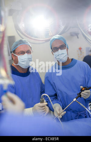 Two male surgeons wearing performing laparoscopic surgery in operating theater Stock Photo