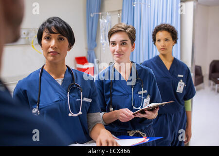 Team of female doctors wearing scrubs talking in hospital ward Stock Photo
