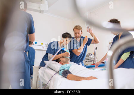 Doctor holding oxygen mask over patient, male doctor adjusting IV drip Stock Photo