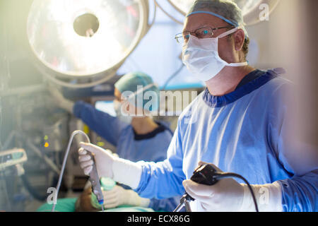 Male surgeon holding laparoscopy equipment during surgery in operating theater Stock Photo