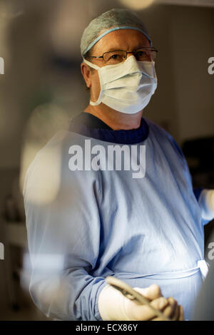 Surgeon wearing surgical mask, cap, gloves and gown in operating theater Stock Photo