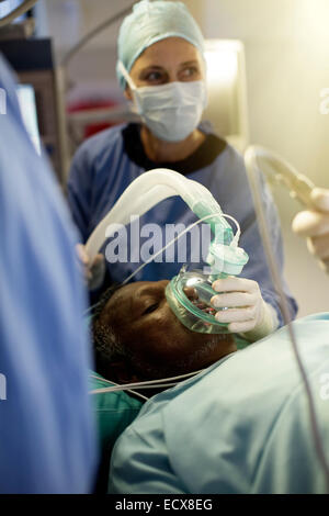 Anesthesiologist holding oxygen mask over patient during surgery Stock Photo