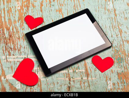 Valentine's Day copy space on digital tablet computer with blank screen and red paper hearts on old grunge wood texture. Stock Photo