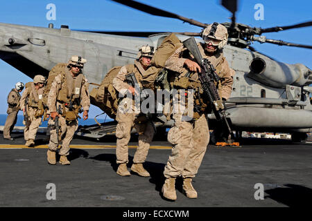 US Marines off-load from a CH-53E Super Stallion helicopter from a mission aboard the Navy amphibious assault ship USS Makin Island December 12, 2014 in the Arabian Gulf. The Makin Island Amphibious Ready Group is participating in Operations against the Islamic State in Iraq and Syria. Stock Photo