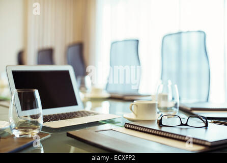 Laptop, eyeglasses and diary on conference table in empty conference room Stock Photo