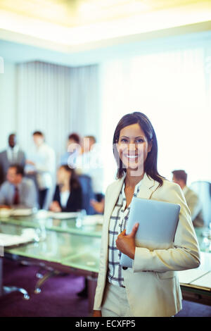 Portrait of businesswoman holding laptop in conference room Stock Photo