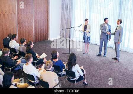Public speakers shaking hands on stage during conference Stock Photo