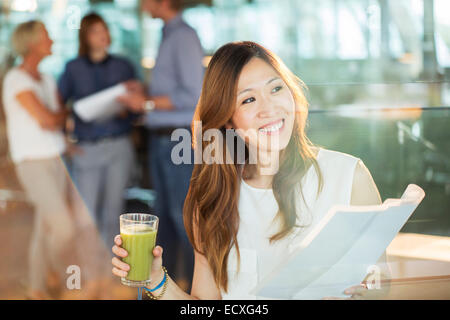 Businesswoman drinking juice and reading paperwork in office Stock Photo
