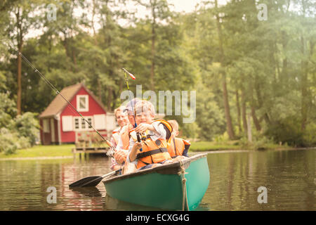 Father and sons fishing from canoe in lake Stock Photo