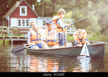 Brothers, father and grandfather fishing from canoe on lake Stock Photo